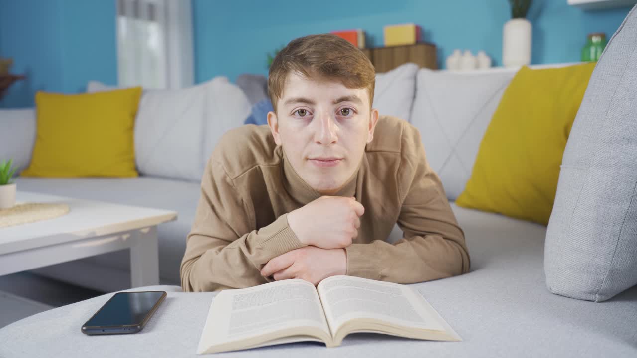 책을 읽는 동안 카메라를 지루하게 바라보는 젊은이.