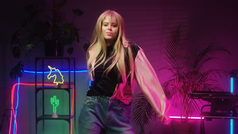 happy teenage girl with long blond hair dancing cheerfully in room with neon lights