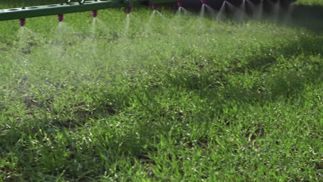 primer plano de las boquillas de pulverización mientras el tractor agrícola aplica pesticidas en el campo con pulverizador