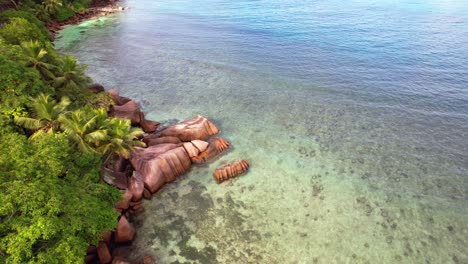 slow moving drone shot of indian ocean, granite rocks, trees and turquoise water on the baie lazare shore, mahe seychelles 30 fps