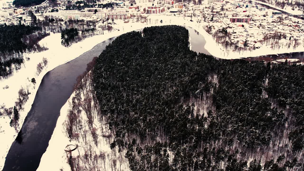 un río sinuoso cerca de un pequeño pueblo con un macizo forestal