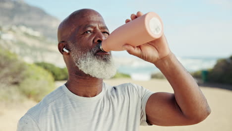 active senior man staying hydrated at the beach