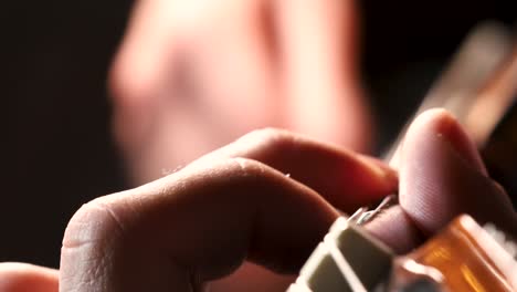 macro shot of male hands playing acoustic guitar chords in dark room