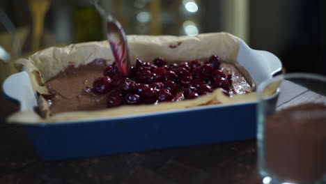 adding cherry to chocolate cake. with spoon. baking ingredient. baking cake