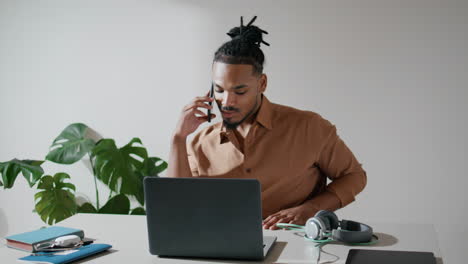 positive freelancer talking phone in light office closeup. man working laptop