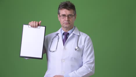 mature handsome man doctor against green background