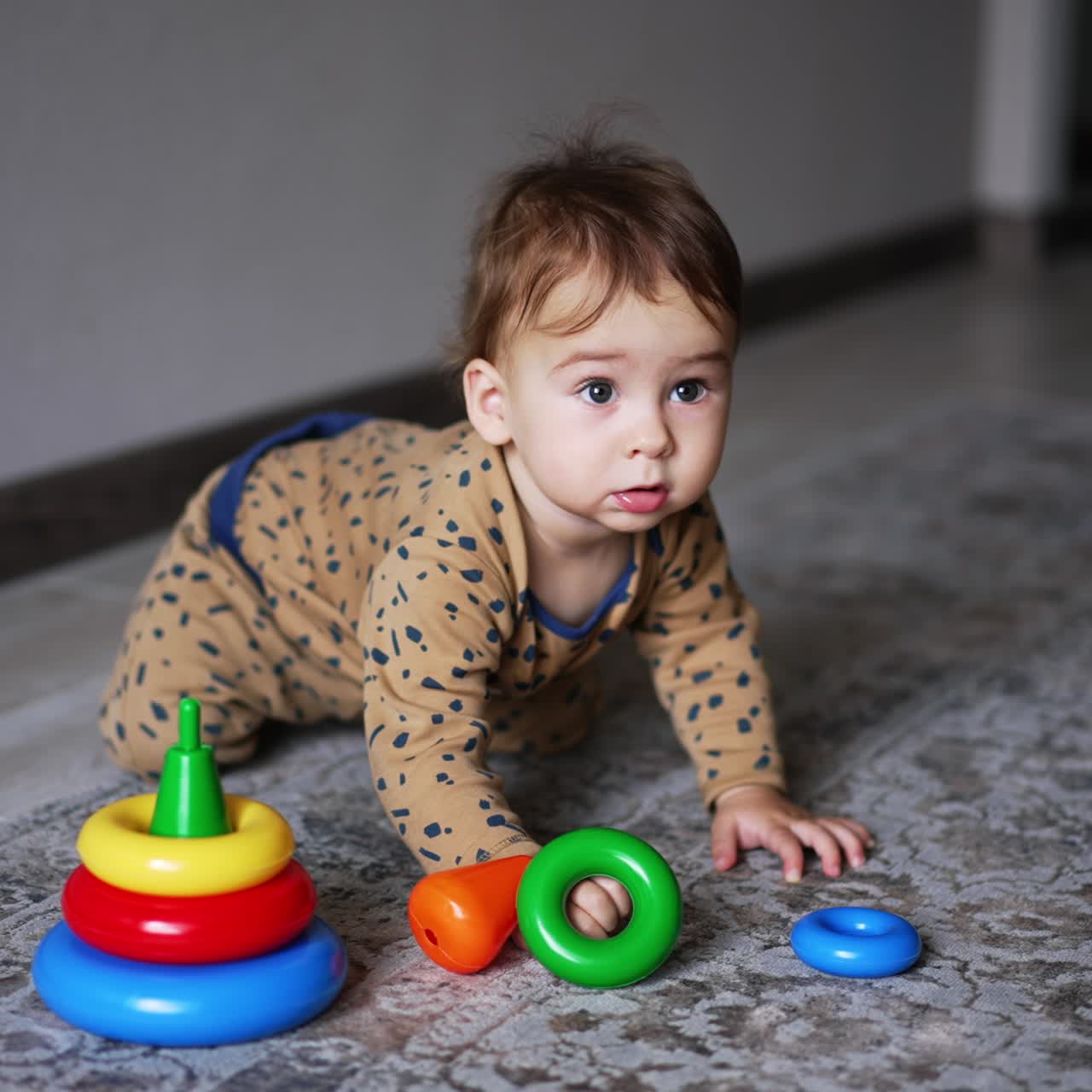 Lovely baby boy crawls up to a toy pyramid on the floor. Sweet kid looks up and continues to crawl. Blurred backdrop
