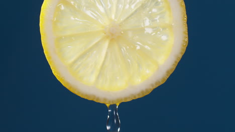 Slow-Motion-Macro-Shot-of-Flowing-Water-from-Lemon-Slice-on-blue-black-Background