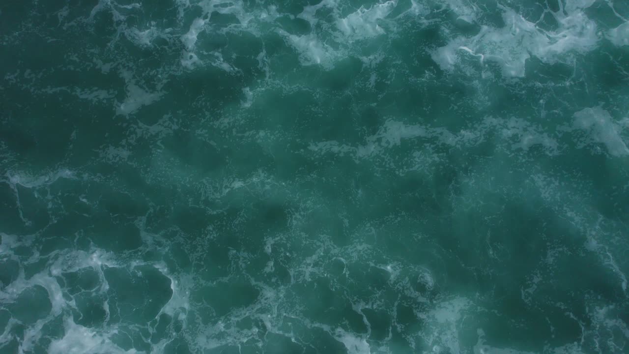 una toma cinematográfica épica de las olas y una playa que se mueve dinámicamente dentro y fuera