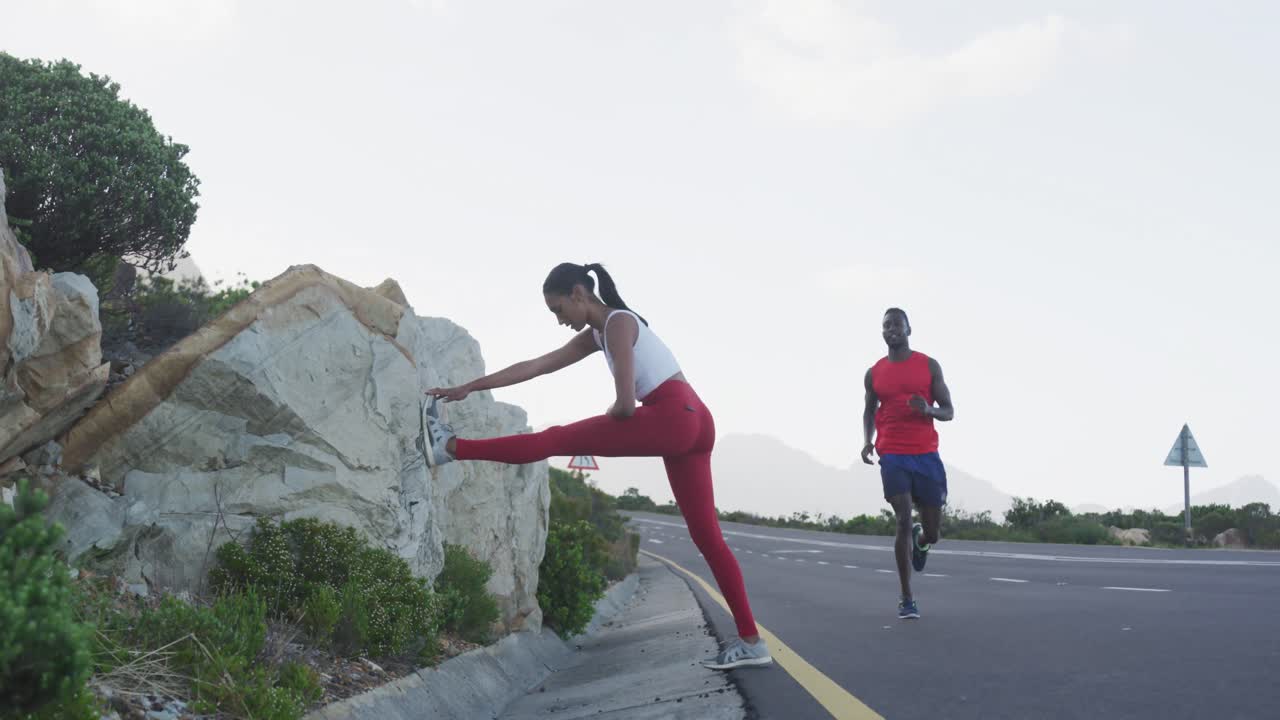 pareja en forma diversa ejercitando estiramiento y corriendo en una carretera de campo