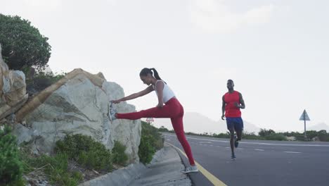 diverse fit couple exercising stretching and running on a country road