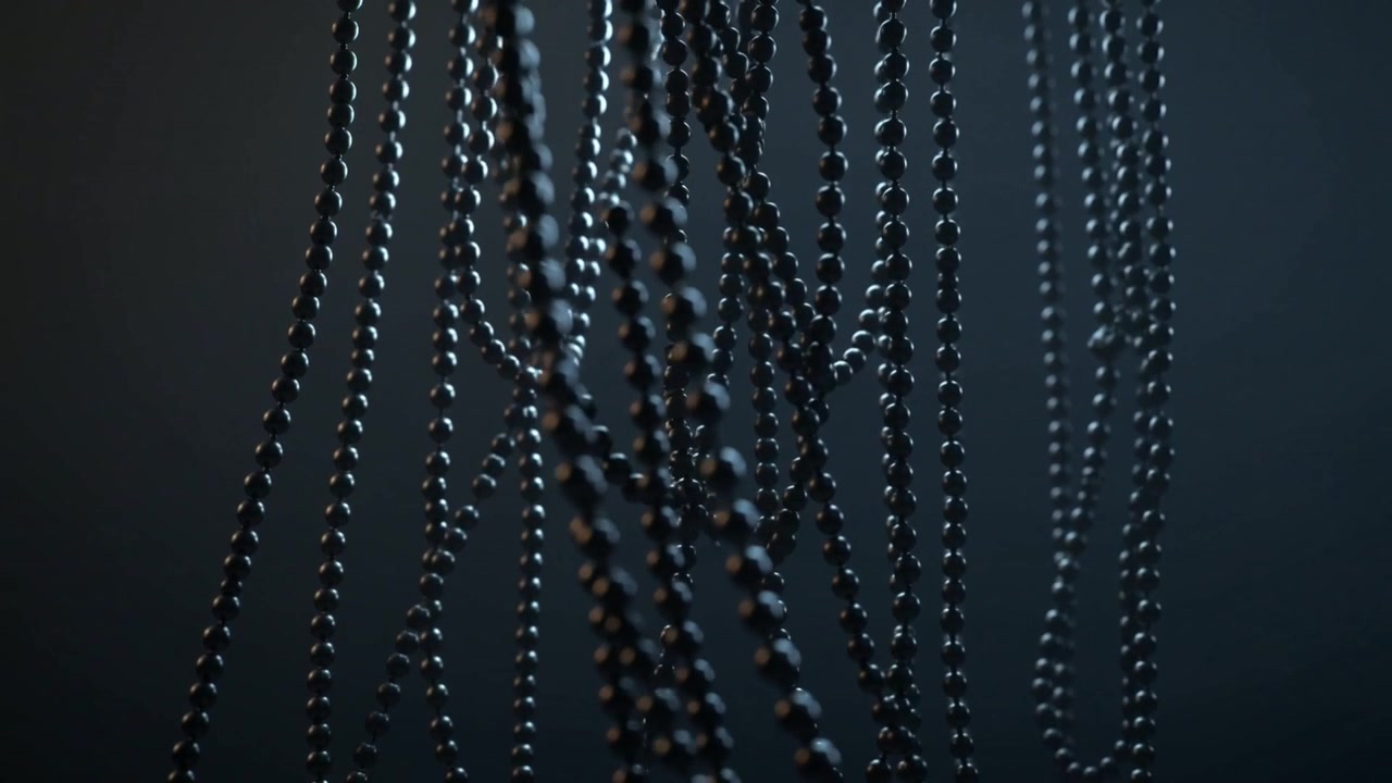 Pulling focus, camera showing metal ball chains swinging into focus at dark studio, rim lighting