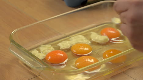 putting milk cream to several eggs with yolk on a glass bowl