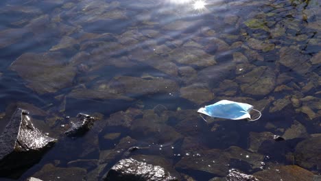 máscara facial descartada utilizada durante la pandemia de covid 19 flotando en el fiordo de noruega
