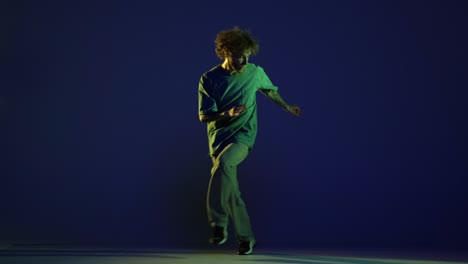 stylish young man, hip-hop dancer dancing isolated over dark blue background in neon light. modern dance art, fashion, youth, ad, style. 4k, video