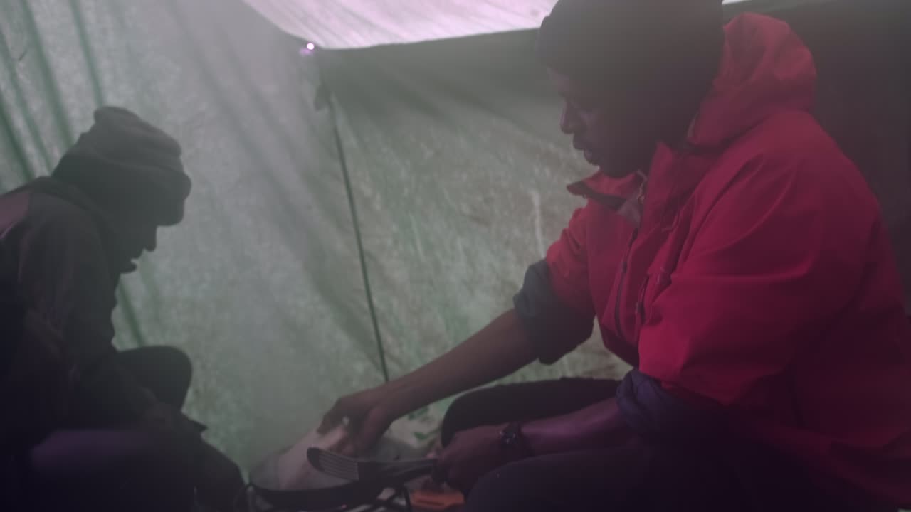 s. A cook prepares lunch by frying toasts on a gas burner in a tent