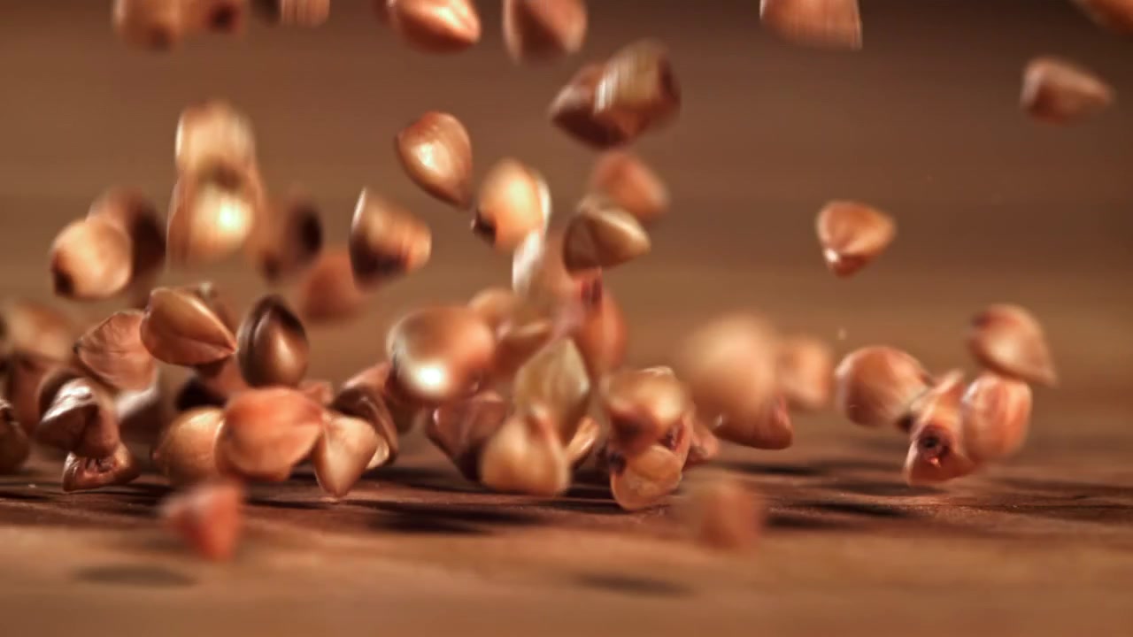 Grani di grano saraceno che cadono al rallentatore su una superficie di legno