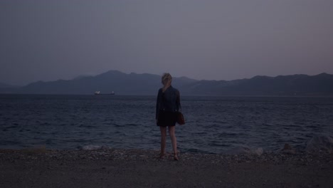woman walking on the beach at sunset, with a ship in the background