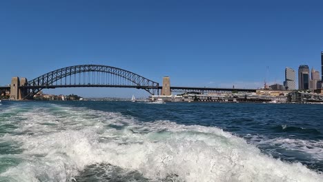 pan across sydney harbour bridge from view of transport ferry boat in water