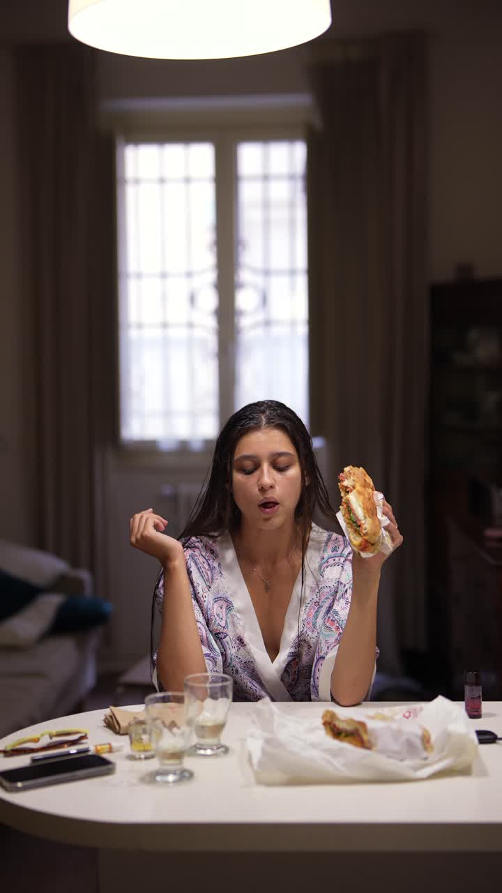 una mujer joven comiendo un sándwich en casa.