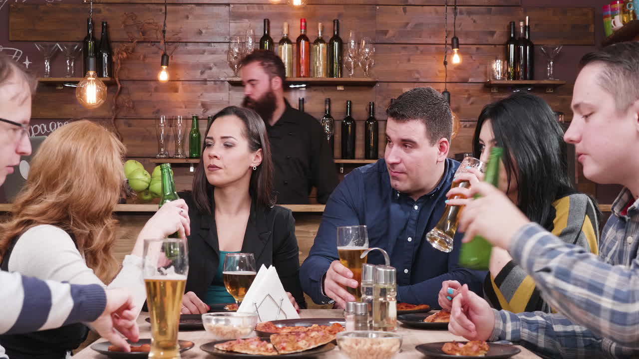 Friends Celebrating with Beer and Pizza at a Bar