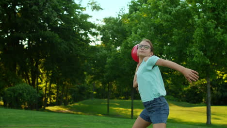 happy girl standing in green field. pretty girl holding ball in hands