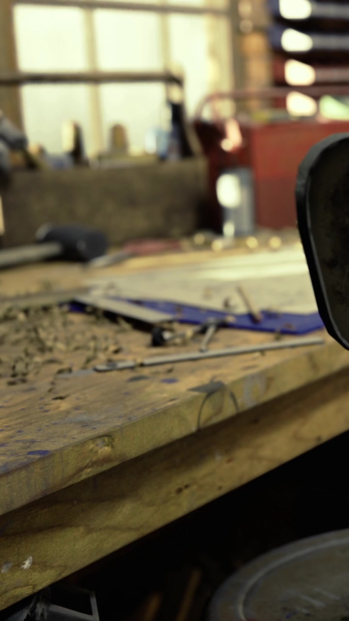 Craftsman works with tools at a workshop bench near various materials