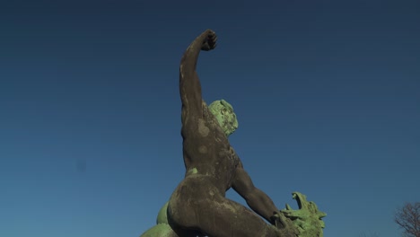statue of a hungarian warrior fighting a three-headed dragon in budapest, hungary with blue sky - tilt down shot