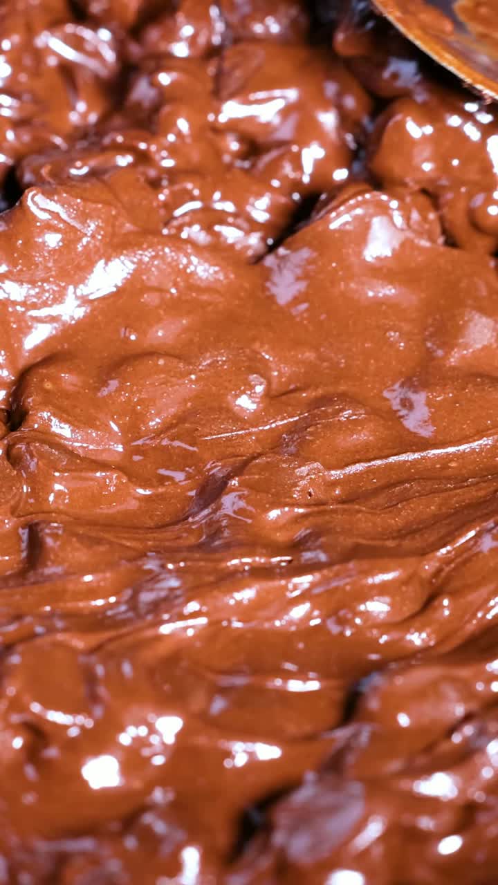 Cucchiaio che mescola delicatamente gocce di cioccolato fuso.