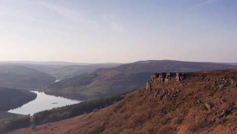 Aerial-Drone-tracking-over-cliffs-with-lake-at-sunset-in-Peak-District-United-Kingdom