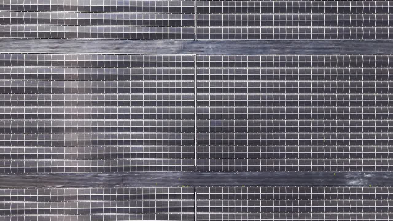Drone footage flying over a large solar farm with photovoltaic panels in a rural landscape, symbolizing renewable energy, sustainability, and climate change solutions for a greener future