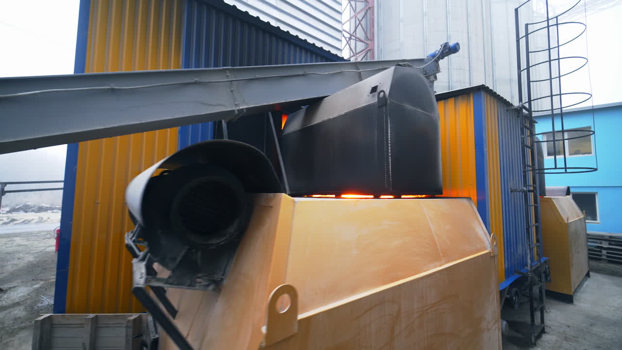 Huge hangar premises for storage and processing crops. Oncoming to the premise with burning fire inside. Modern industrial factory exterior.