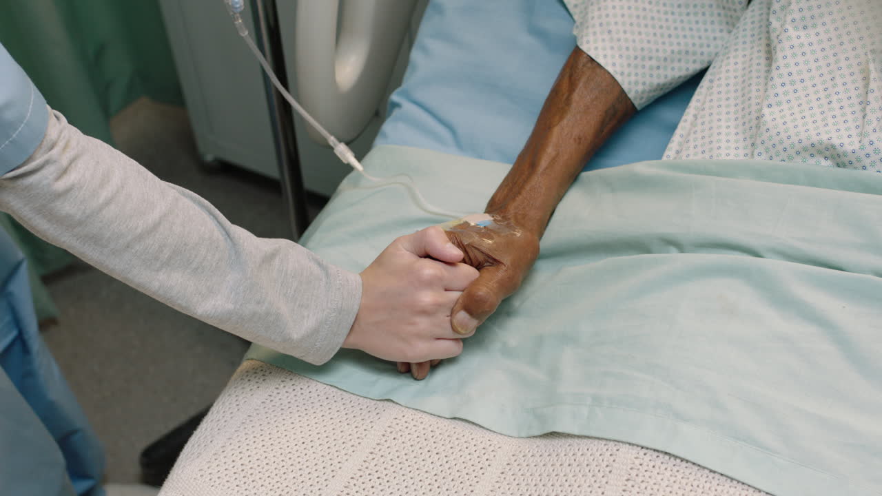 vista superior enfermera sosteniendo la mano de un anciano en la cama del hospital mostrando afecto por el paciente anciano que se recupera de la enfermedad