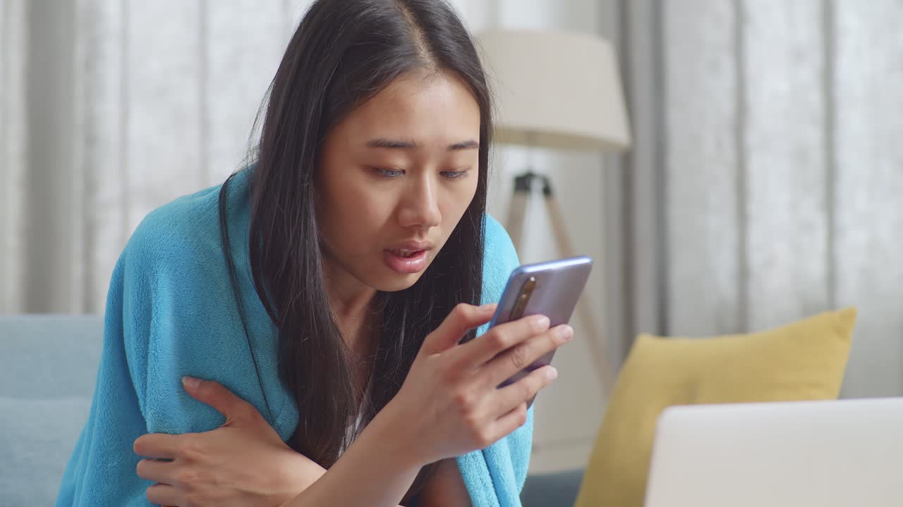 담요 에 싸여 있는 여자 가 드폰 을 보고 있다