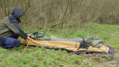 Putting-up-his-tent,-a-camping-enthusiast-is-meticulously-putting-each-part-together-at-a-campground-located-at-Thetford-forest