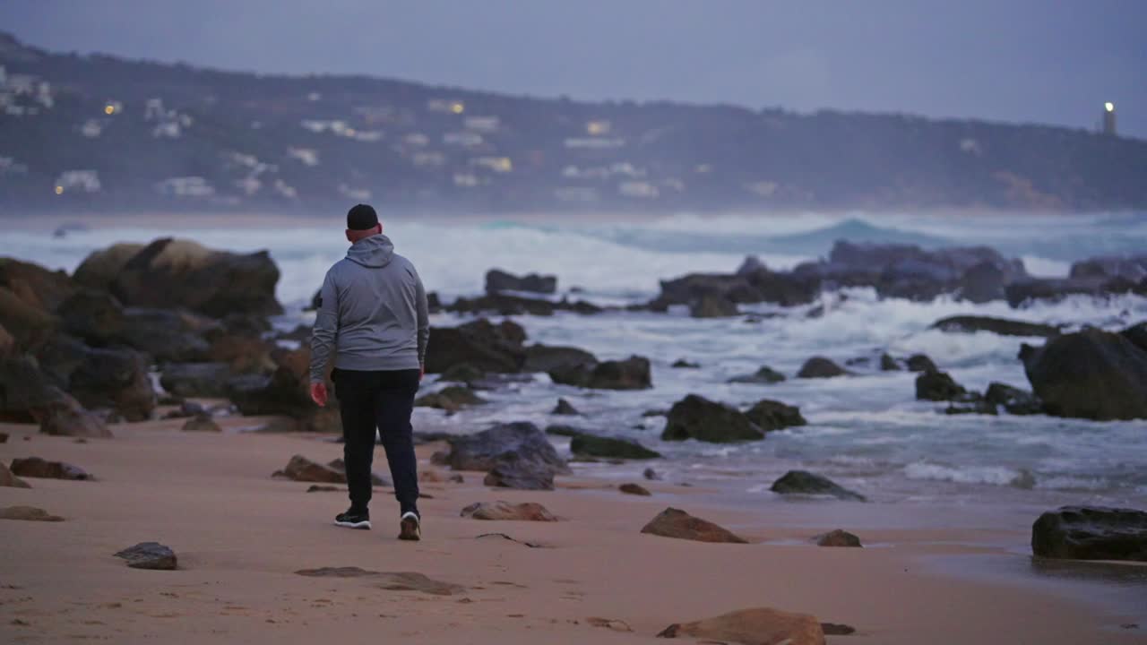 Viandante solitario su un litorale roccioso al tramonto