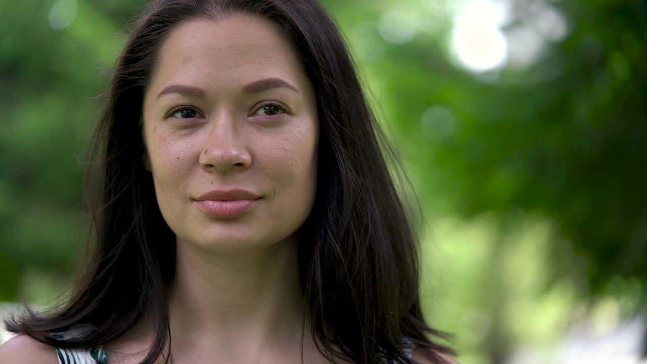 un retrato de una linda mujer asiática parece pensativo. un viento débil sopla su cabello. sonrisa ligera.