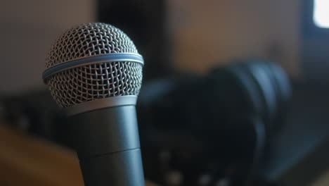 cinematic static close up shot of a professional dynamic microphone, rotating slowly in a home recording studio.