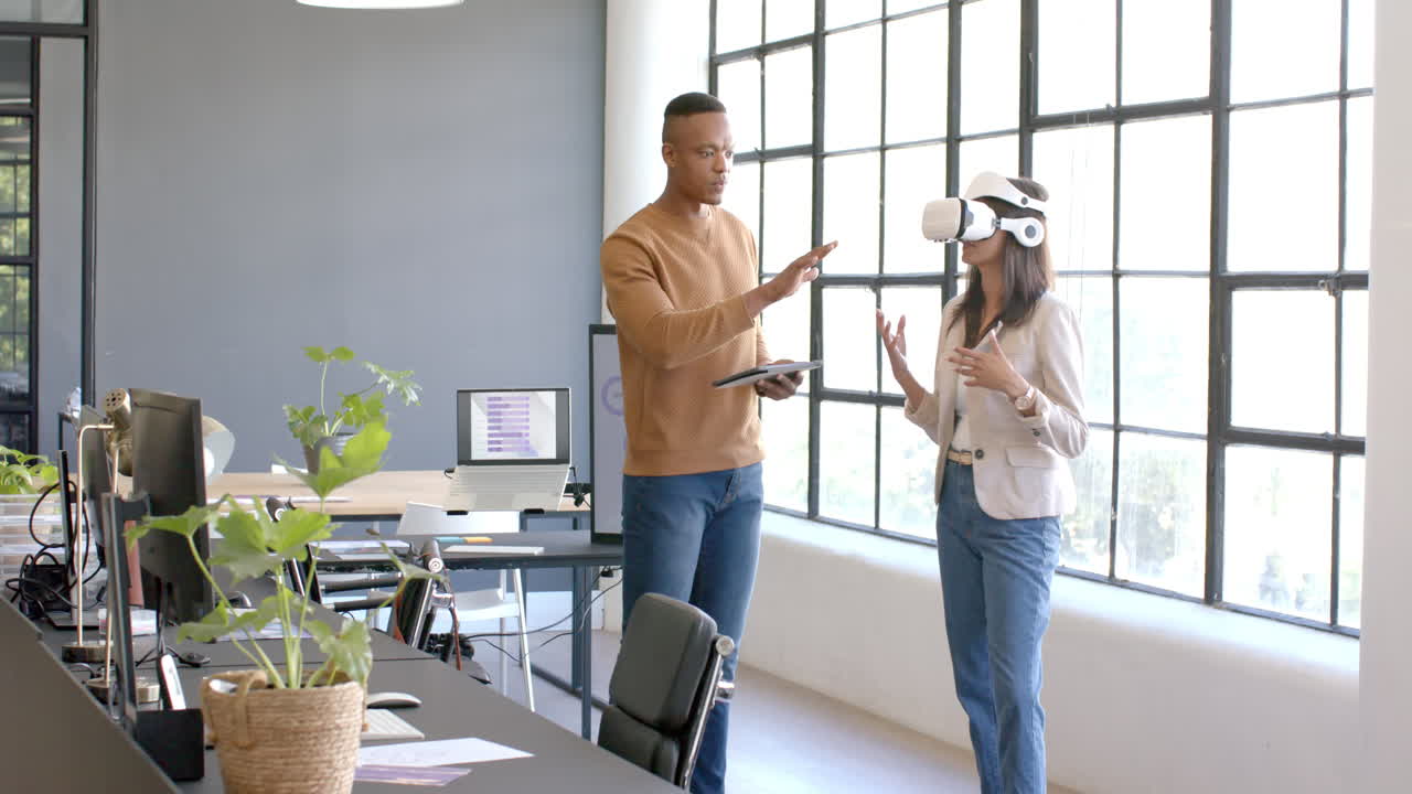 Using VR headset, business colleagues discussing project in modern office setting
