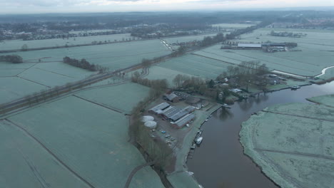 aerial of farm on river shore in a beautiful frost covered landscape