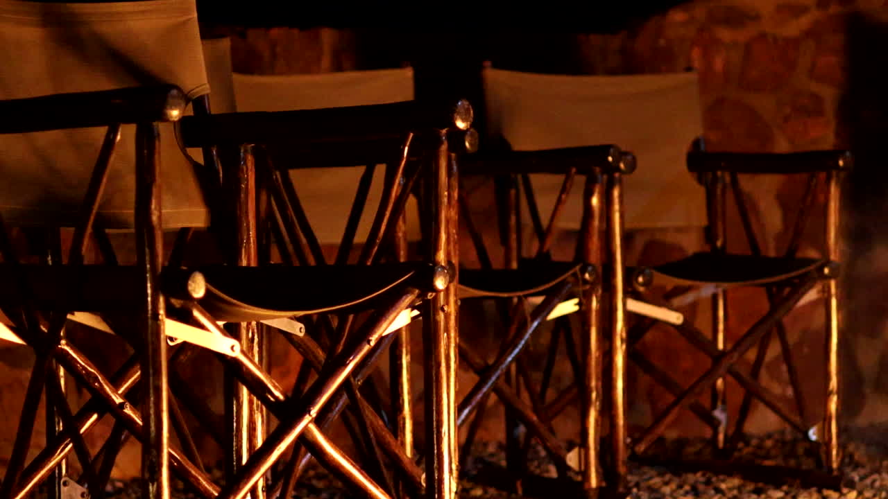 Directors Chairs reflect the warm flickering campfire light at night, peaceful and rustic ambiance - no people