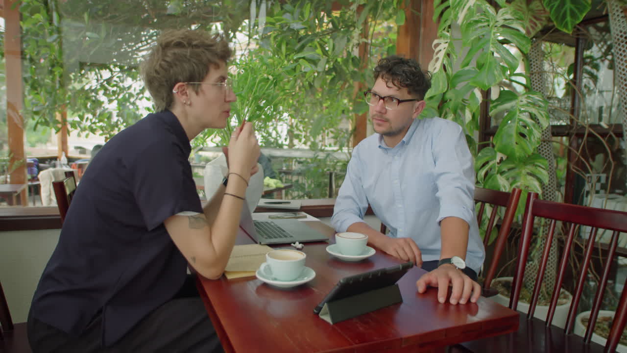 Business Partners Using Tablet and Talking in Outdoor Cafe