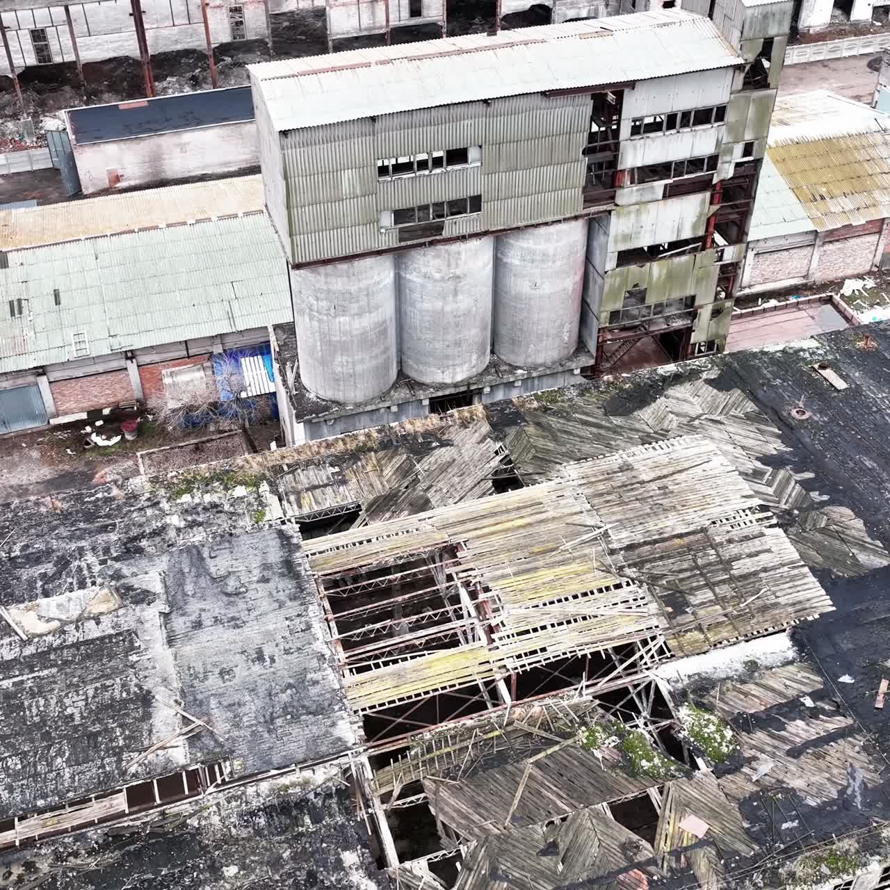 Warehouses of an old plant. Aerial perspective on the wrecked roof of a long empty warehouse in the industrial area