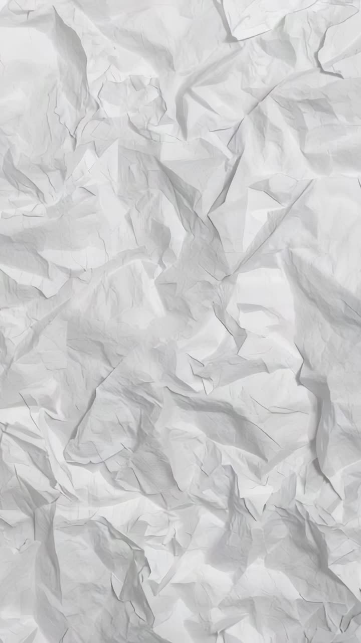 Vertical video: Shifting camera showing crumpled white sheet in studio, revealing folds and texture
