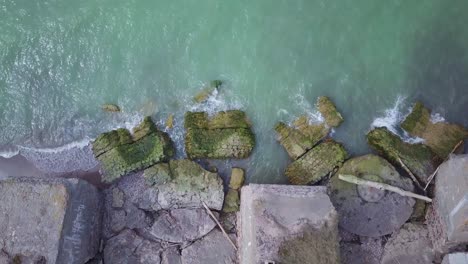 Aerial-birdseye-view-of-abandoned-seaside-fortification-buildings-at-Karosta-Northern-Forts-on-the-beach-of-Baltic-sea-in-Liepaja,-Latvia,-calm-sea-on-a-sunny-day,-wide-angle-rotating-drone-shot