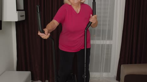 Active-healthy-senior-old-mature-woman-in-sportswear-using-orbitrek,-training-cardio-workout-at-home