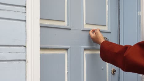 una persona llamando a una puerta azul