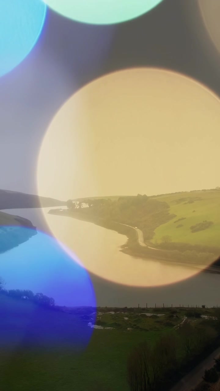Video verticale: Dischi bokeh colorati che appaiono, scorrono, si mescolano e svaniscono, rivelando un'ansa del fiume e una strada.