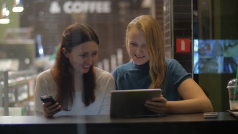 Amigas-Entretenidas-Con-Pad-En-La-Cafetería.