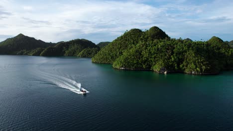 Small-boat-drives-through-in-Raja-Ampat-Indonesia,-in-between-tropical-islands,-turquoise-waters,-and-coral-reefs